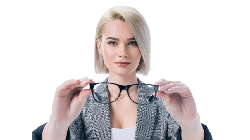 Mlada žena drži ispred sebe naočare sa dioptrijom.